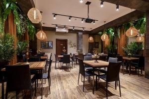 a restaurant with tables and chairs and plants at Hotel City in Tbilisi City