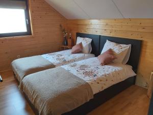 2 camas en una habitación con paredes de madera en Le refuge Ardennais en Libramont