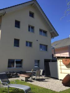 a large white building with chairs and a table at FeWo-Studio Linde in Amsoldingen