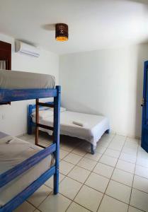 um quarto com 2 beliches e piso em azulejo em Vila Mucugê Pousada e Hostel em Arraial d'Ajuda