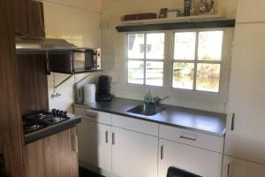eine Küche mit weißen Schränken, einem Waschbecken und einem Fenster in der Unterkunft Blokhut De Vlinder gelegen nabij het Pieterpad in Coevorden