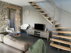 een woonkamer met een bank en een trap bij Au p’tit loup in Bastenaken