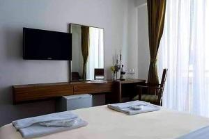 a bedroom with a bed with a television and a desk at Hotel Scardus in Tetovo