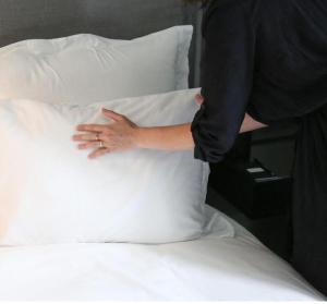 a person putting their hand on a pillow on a bed at La Guta Studio Suite The Campari Suite in Jerusalem