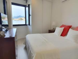 ein weißes Schlafzimmer mit einem großen Bett und einem Fenster in der Unterkunft Seashore House " Es tamarells" in Alcúdia