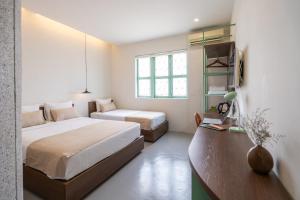 a hotel room with two beds and a desk and a bed sidx sidx sidx sidx at La Memoria Hotel - City Centre in Ho Chi Minh City
