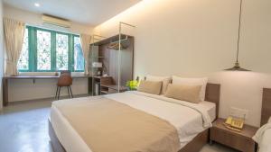 a bedroom with a large white bed and a desk at La Memoria Hotel - City Centre in Ho Chi Minh City