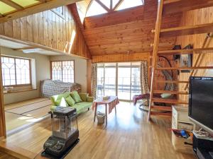 a living room with a green couch and a tv at Asuka's House 八ヶ岳 in Hokuto