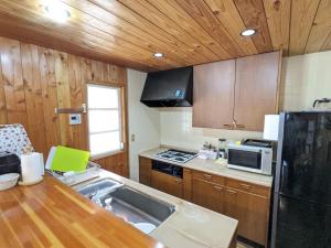 a kitchen with wooden cabinets and a sink and a refrigerator at Asuka's House 八ヶ岳 in Hokuto