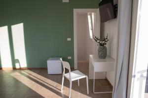 een kamer met een stoel, een tafel en een spiegel bij Largo Sicilia B&B in Avola