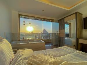 um quarto com uma cama, uma banheira e uma janela em Best View Pyramids Hotel em Cairo