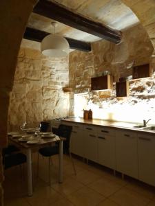 a kitchen with a table and a stone wall at 3Cities Maison close to Valletta in Cospicua