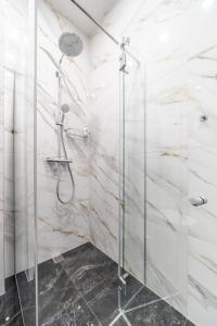W łazience z białymi marmurowymi ścianami znajduje się prysznic. w obiekcie New Comfortable 2 Bedroom Cottage w/Big Terrace w Jurmale