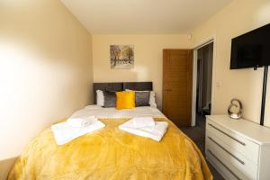 a bedroom with a bed with two towels on it at Central Windsor Stunning 4 Bedroom Spacious Modern House in Windsor