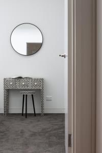 a mirror on a wall above a table with a stool at Stylish 2-Bed Apartment with BBQ Patio Near Beach in Sydney