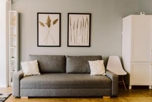 een woonkamer met een grijze bank en twee foto's aan de muur bij 701 DISTRICT in Mamaia Nord – Năvodari