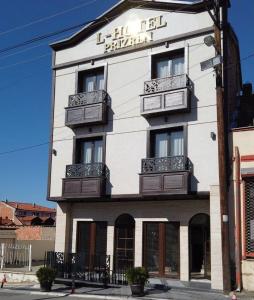 een hoog wit gebouw met een bord erop bij L'Hotel in Prizren