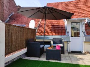 un patio avec deux chaises et un parasol dans l'établissement Joli petit T2 terrasse proche du phare, à Calais