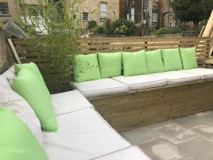 a wooden bench with green pillows on a patio at Gorgeous Garden Apartment in Bath