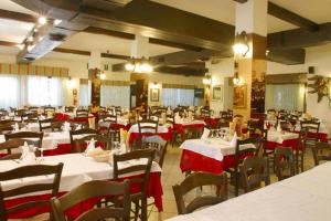 a dining room with white tables and chairs with red table cloth at Albergo Ristorante Da Giuseppe in Copparo