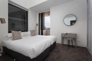 Schlafzimmer mit einem Bett, einem Spiegel und einem Tisch in der Unterkunft Stylish 2-Bed Apartment with BBQ Patio Near Beach in Sydney