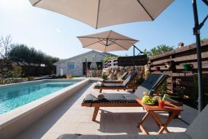 a swimming pool with lounge chairs and an umbrella at Haus Vita in Pula