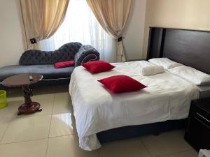 a bedroom with a bed with red pillows and a couch at Martyrs Guest House in Vanderbijlpark