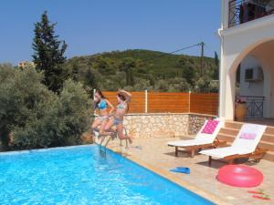 two women in bathing suits jumping into a swimming pool at Villa Katia in Tsoukalades