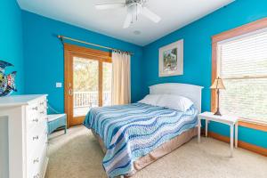 a blue bedroom with a bed and a window at Luv Shack in Corolla