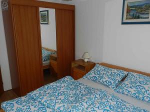a bedroom with a blue and white bed and a mirror at Two-Bedroom Apartment in Malinska I in Sveti Vid-Miholjice