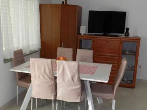 a dining room table with chairs and a television at Two-Bedroom Apartment in Malinska I in Sveti Vid-Miholjice