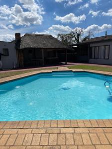 a large blue swimming pool in front of a house at Martyrs Guest House in Vanderbijlpark