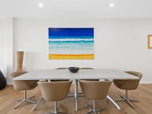 a dining room table with chairs and a painting at Oceania 3 in Lorne