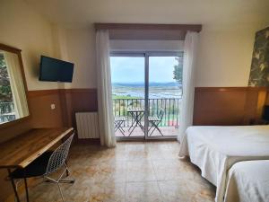 a bedroom with a bed and a view of a balcony at Hotel Ría de Suances in Suances