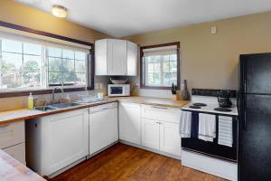 a kitchen with white cabinets and a black refrigerator at Sweet Netarts in Tillamook