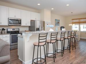 a kitchen with white cabinets and a bar with stools at Seaside Village - Bowline in Ocean City