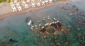eine Luftansicht auf einen Strand mit Menschen im Wasser in der Unterkunft Tsambikos Apts in Faliraki