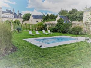 a yard with a swimming pool and chairs in the grass at Cottage de la Tour - Duplex troglodyte of 100 m in Azay-le-Rideau