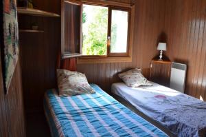 Saint-Antoine-de-BreuilhにあるChalet En Bord De Rivièreのベッド2台と窓が備わる小さな客室です。
