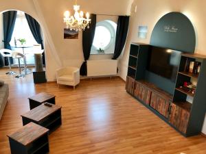 ein Wohnzimmer mit einem Flachbild-TV und Holzböden in der Unterkunft Villa Sturm Rüdesheim am Rhein in Rüdesheim am Rhein