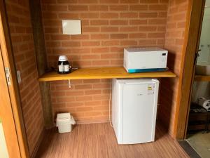 Una pequeña cocina con microondas y nevera. en Chalés Roma, en Santo Antônio do Pinhal 4 fotos más