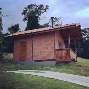 een klein gebouw met een veranda op een veld bij Chalés Roma in Santo Antônio do Pinhal