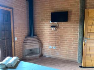 pared de ladrillo con chimenea de ladrillo y TV en Chalés Roma, en Santo Antônio do Pinhal