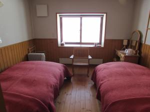 Dos camas en una habitación con ventana. en ポロト案内舎, en Hamanaka
