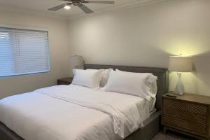 a bedroom with a bed with white sheets and a ceiling fan at City Center Villa - Pool, Patio & Close To Beach! in Huntington Beach