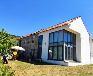 a house with large windows and an umbrella at Turismo Rural Macieira Brava in Guarda