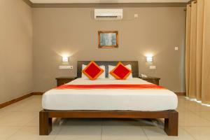 a bedroom with a large bed with two orange pillows at Kings Ridge Kandy in Kandy