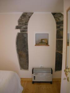 a bedroom with a stone wall with a bed and a radiator at Welcome to Casa Terracotta a cosy self-catering holiday home. in Masanti