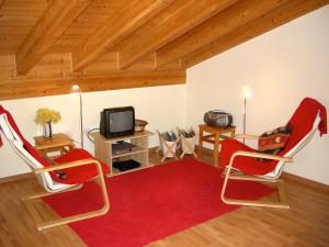 a living room with two red chairs and a tv at Welcome to Casa Terracotta a cosy self-catering holiday home. in Masanti