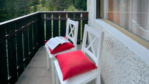 ノーヴァ・レヴァンテにあるBrand new 70sqm apartment, 1 km from Lake Carezza, in the Dolomitesのバルコニー(赤いクッション付きの椅子2脚付)